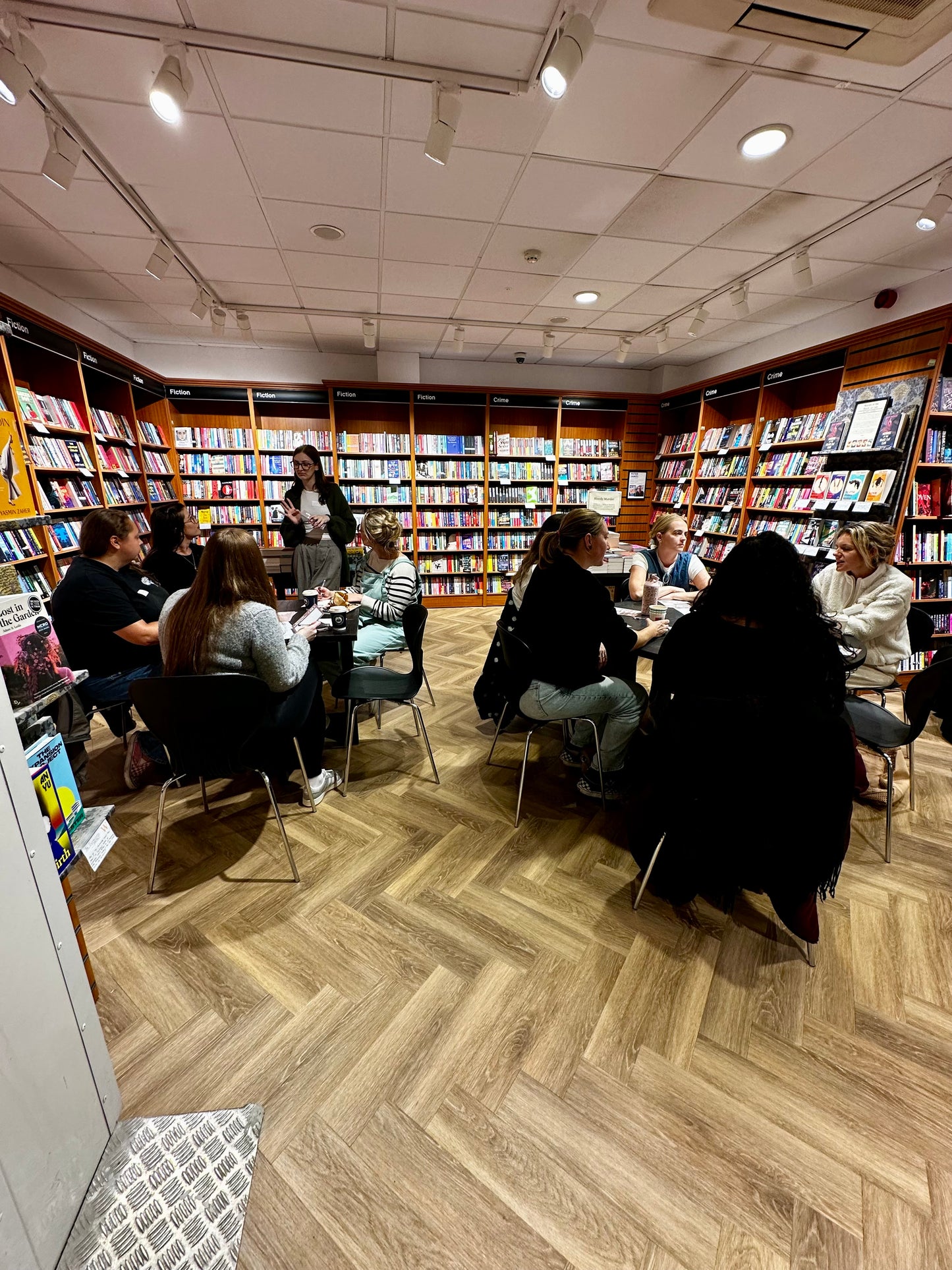 Group of people sitting in a bookstore with bookshelves lining the walls.