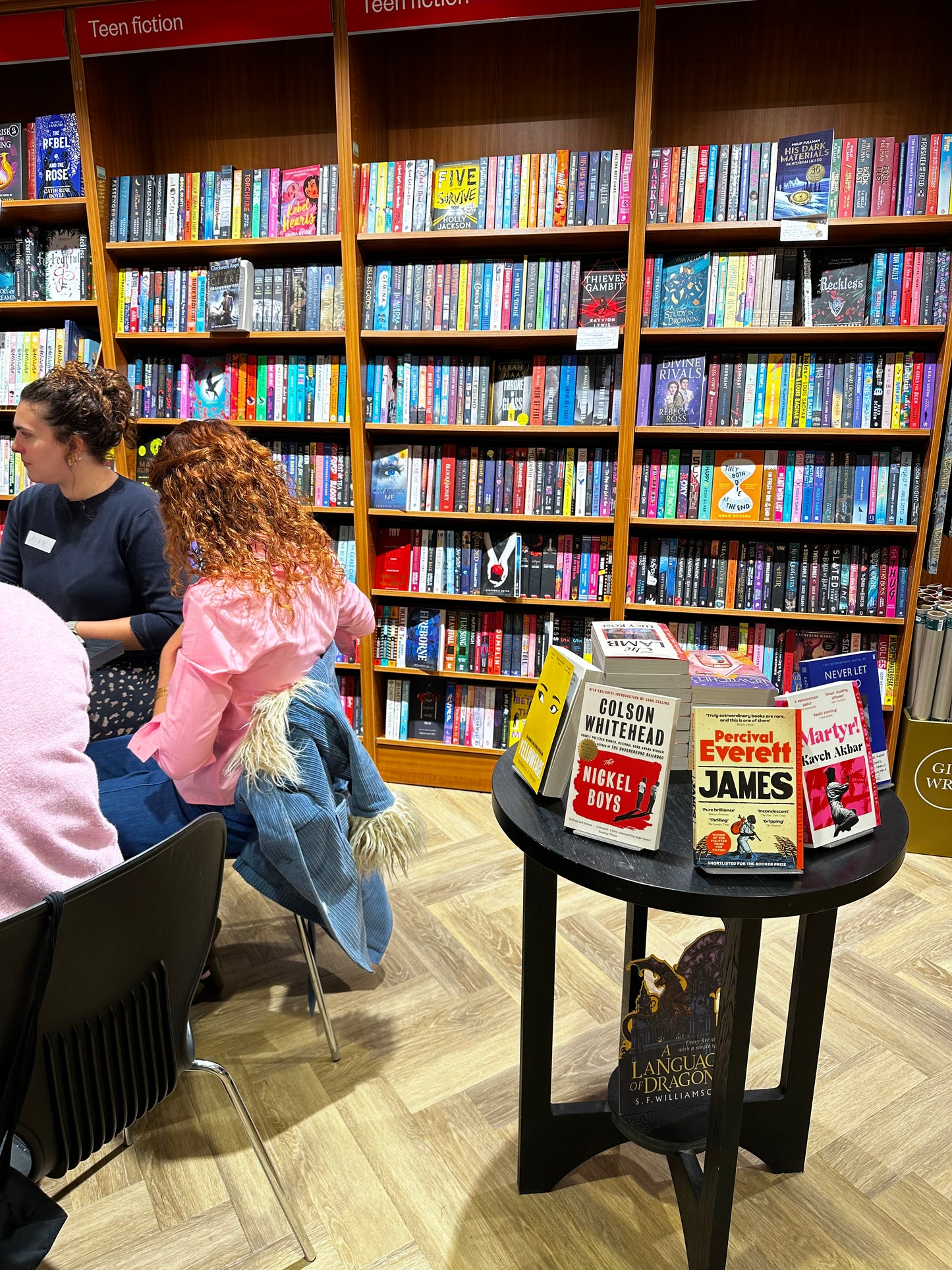 Book club members sitting at tables in a bookshop.